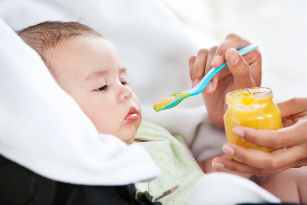 Close-up of a mother giving food to her adorable baby at home.jpeg